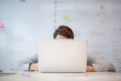 Businessman looking at laptop screen while sitting at table in creative office. Getty Images