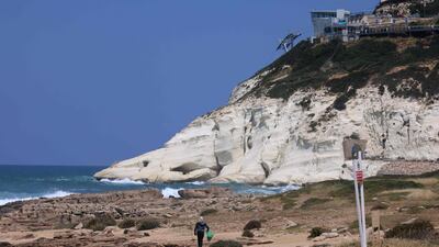 A garbage collector walks towards the Rosh Hanikra grottoes on the Israeli-Lebanese border in Rosh Hanikra. The grottoes are a geologic formation on the Israel-Lebanon border, along the Mediterranean coast. AFP
