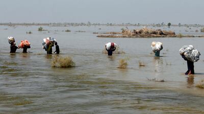 Victims of heavy flooding carry relief aid through flood water in the Qambar Shahdadkot district of Sindh province, Pakistan, September 9, 2022. AP Photo