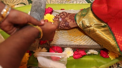 The groom makes offerings of flowers as the bride steps on a stone as part of the marriage ceremony