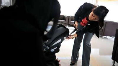 Amira Wali shows a woman picking up her free car seat at Corniche Hospital's Newborn Safety Centre how it works.