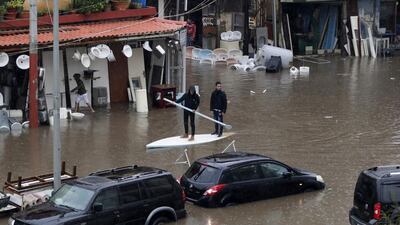Lebanese men use a paddle board as means of transportation on a flooded road due to heavy rain, at the southern entrance of the capital Beirut. AFP