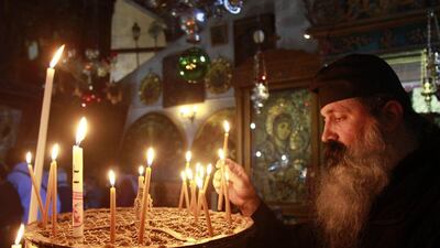 Palestinian Territories: A Greek Orthodox priest lights a candle in the Church of the Nativity in the West Bank biblical town of Bethlehem. AFP Photo/Musa Al-Shaer