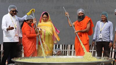 Indian chef Sanjeev Kapoor, left, minister for food processing Harsimrat Kaur Badal, centre, minister of state for food processing industries Sadhvi Niranjan Jyoti, second from left, and yoga guru Baba Ramdev, second from right, stir a giant pan of khichdi at World Food India in New Delhi on November 4, 2017. Rajat Gupta / EPA