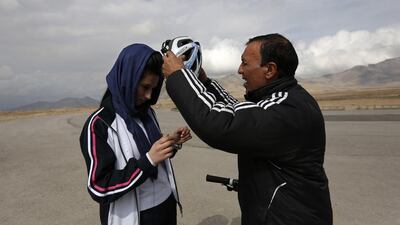 Coach Abdul Sadiqi assists Malika Yousufi with her helmet. Mohammad Ismail / Reuters