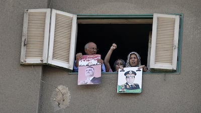 Residents of Cairo hold out posters of the late president Gamal Abdel Nasser, left, and the current military chief, Gen Abdel Fattah El Sisi, while watching a protest by supporters of the Muslim Brotherhood last Friday. Hassan Ammar / AP Photo