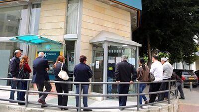 Despite public outcry and the scrapping of a plan to levy all bank accounts in Cyprus, accounts holding more than €100,000 will still be tapped into by the government to help to meet terms of an EU bailout. Above and below, Cypriots queue to withdraw money. Patrick Baz / AFP