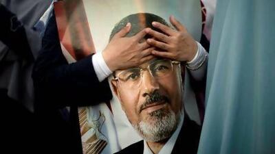 An Egyptian supporter of the Muslim Brotherhood holds a picture of deposed president Mohamed Morsi outside Cairo's Rabaa al-Adawiya mosque on July 5, 2013. Supporters of ousted Egyptian president Mohamed Morsi took to the streets in their tens of thousands, defying his army deposers and triggering running clashes that killed at least three people. AFP PHOTO/MAHMUD HAMS *** Local Caption *** 499088-01-08.jpg