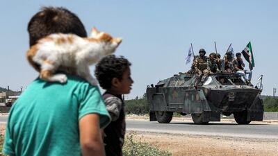 A boy with a kitten on his shoulder watches Turkish-backed Syrian rebel fighters from Tal Rifaat heading for the Azaz frontlines in the northern Aleppo province. AFP