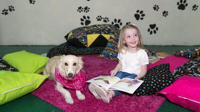 A girl reads with Adelaide the Mixed Breed Reading Dog. Adelaide is currently being trained by Reading Dogs Abu Dhabi. Reem Mohammed / The National