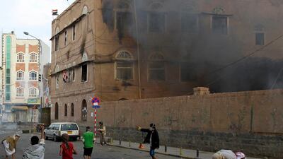 Anti-government protesters throw rocks at police as smoke rises from a government building during clashes in Sanaa on September 18, 2011. At least 20 protesters were killed when security forces fired on one of the biggest demonstrations against President ???