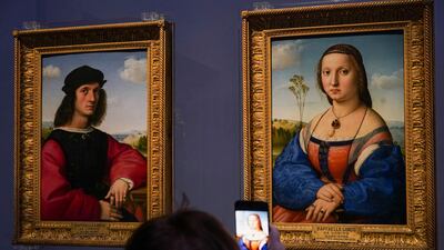 A member of the media takes pictures of 15th century paintings 'Portraits of Angelo', left, and 'Maddalena Doni' by Raffaello Sanzio da Urbino. AP Photo