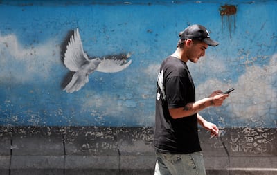 An Iranian man walks past a painting of a dove in a street in Tehran on June 24, 2025. EPA