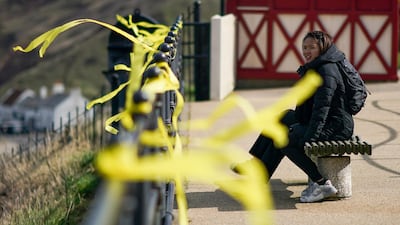 Two women sit near yellow ribbons tied to railings on the promenade at Saltburn to mark the National Day of Reflection. Getty Images