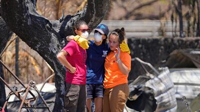 Women console each other after digging through the rubble of a home destroyed by the wildfire in Lahaina, Hawaii. AP