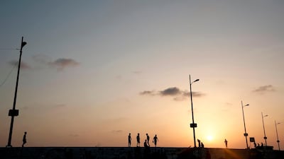 Palestinians walk by the sea at sunset in Gaza City. AFP