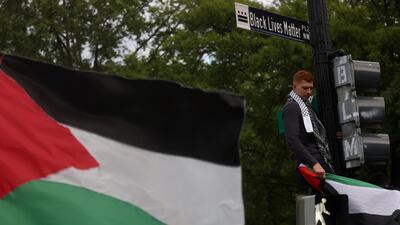Moustafa Almeky stands on a street light as he joins fellow pro-Palestinian demonstrators outside the White House after marching from the US State Department building in Washington. Reuters