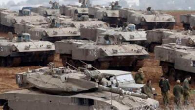 Israeli soldiers stand near armoured military vehicles at a staging area just outside the northern Gaza Strip.