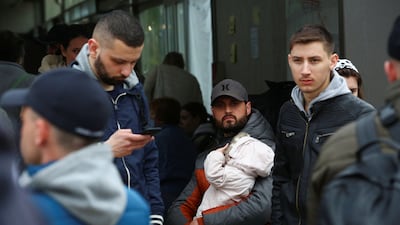A Ukrainian man holds a baby at US-Mexican border as he waits to cross into the US. Reuters