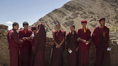 Buddhist monks from the Drukpa lineage hold their voting cards as they wait outside a polling station to vote near the Hemis Monastery.