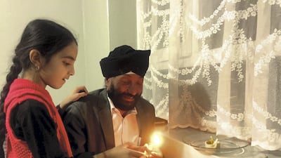 Rawail Singh helps his daughter light a lamp to mark Diwali at their home in Kabul on October 18, 2017. Ruchi Kumar