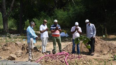 People pray next to the grave of their relative, who died from the Covid-19 Coronavirus, at a graveyard in New Delhi on September 27, 2020. AFP