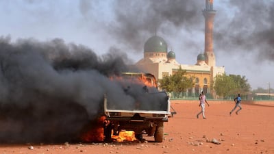 People run past a police truck set on fire by protesters during a demonstration against French weekly Charlie Hebdo's publication of a cartoon of the Prophet Mohammed in front of the grand mosque in Niamey on January 17, 2015. Boureima Hama/AFP Photo