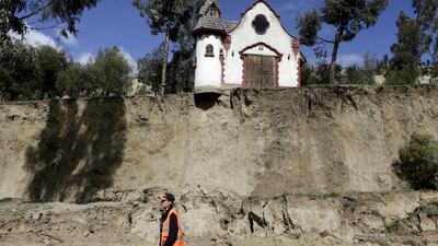 A worker walks in front of a chapel on February 29, 2016, after a landslide caused by heavy rain in Jupapina, on the outskirts of La Paz, Bolivia. David Mercado / Reuters