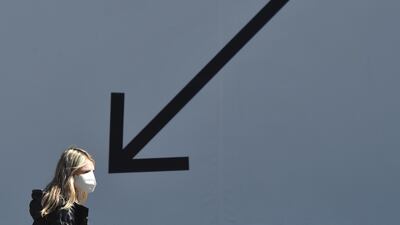 A young woman wearing a face mask walks past an advertising placard in the Ukrainian capital of Kiev. AFP