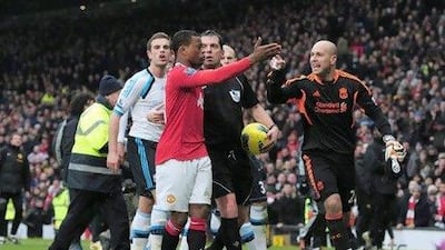MANCHESTER, ENGLAND - FEBRUARY 11: Patrice Evra of Manchester United is led away from Liverpool players by referee Phil Dowd as he celebrates victory after the Barclays Premier League match between Manchester United and Liverpool at Old Trafford on February 11, 2012 in Manchester, England. (Photo by Shaun Botterill/Getty Images)