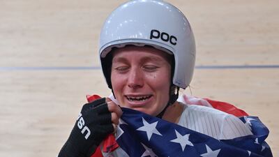 Gold medallist USA's Jennifer Valente reacts as she poses with a flag after the women's track cycling omnium points race.