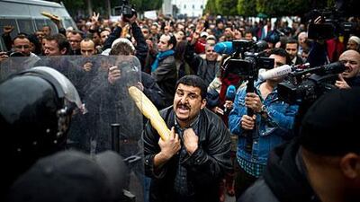 A protester armed with a baguette talks to riot police during a demonstration in Tunis on January 18.