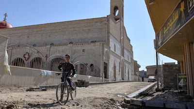 A boy stands with his bicycle by the Syriac Catholic Church of the Immaculate Conception (al-Tahira-l-Kubra), in the predominantly Christian town of Qaraqosh. AFP