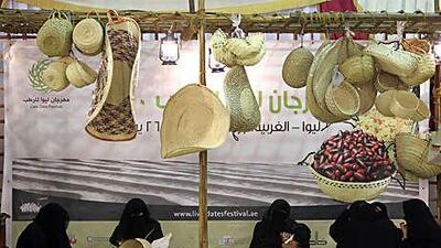 Women weave straw baskets and mats out of palm leaves, a traditional handicraft in the UAE, at the Liwa Date Festival.