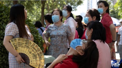 Parents wearing masks to limit the spread of the coronavirus wait in the shade as their children take part in their college entrance exams in Beijing, China. AP Photo