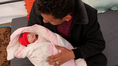 Khalil Al Suwadi holds his niece, Afraa, who was born under the rubble in northern Syria. AFP