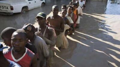 People line up in mud for water and food at a shelter for flood victims after Tropical Storm Hanna hit Gonaives, Haiti, on Sept 5.