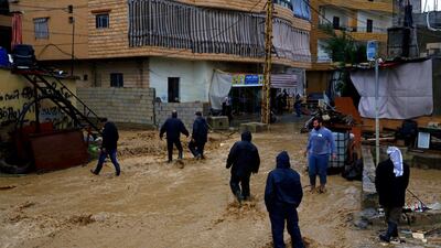 People cross a mud-flooded street in Beirut. AP Photo