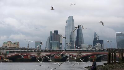 A woman feeds birds on the bank of the river Thames with London's financial district seen in the background. While the UK economy has now grown for six months running, it still remains 7.9% below pre-pandemic levels. Reuters