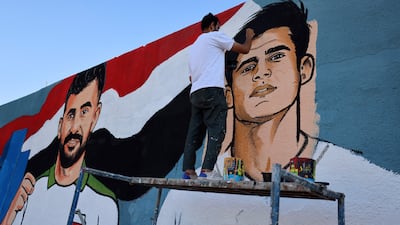 A street artist paints a mural of Iraqi midfielder Ibrahim Bayesh, right, alongside forward Aymen Hussein in Sadr City, east of Baghdad, on Monday. Iraq, whose preparations were disrupted by the war in the Middle East, have sealed their first appearance at the World Cup in 40 years. AFP