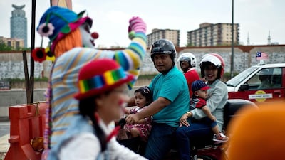 A Malaysian family watches as clowns take part in a parade during the Clown Festival.