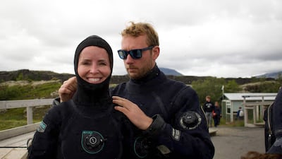 Diving instructor Lorenzo (R) helps a Canadian tourist (L) to put on her hood before a snorkelling tour on July 26, 2022 in Thingvellir, Iceland. - In between North American and Eurasian tectonic plates, Iceland's Silfra fissure is one of the world's most famous dive sites, popular with tourists who venture into its icy waters. (Photo by Jeremie RICHARD / AFP) / TO GO WITH AFP STORY BY JEREMIE RICHARD