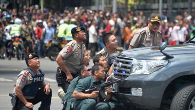 Indonesian police take position behind a vehicle after a series of blasts hit the Indonesia capital Jakarta on the morning of January 14, 2016. Bay Ismoyo / AFP