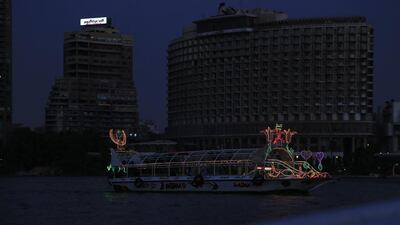 A boat sails along the Nile river, in Cairo on September 5, as the Garden city neighborhood, background, remains in darkness during a power cut. AP