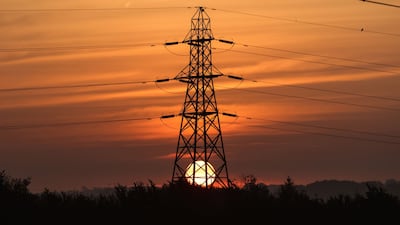 The sun rises behind an electricity transmission tower in the UK. Bloomberg