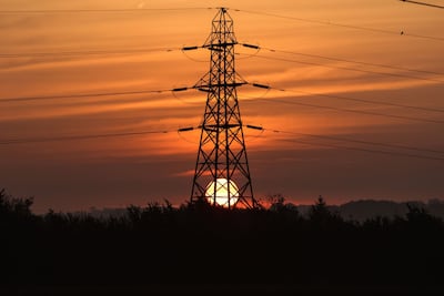 The sun rises behind an electricity transmission tower in the U. K. Photographer: Chris Ratcliffe / Bloomberg