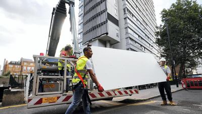 Workers remove panels of external cladding from the facade of a London high-rise block in July 2017 following the Grenfell Tower blaze. AFP