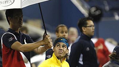 Rafael Nadal sits under an umbrella during his rain-interrupted match with Fernando Gonzalez.