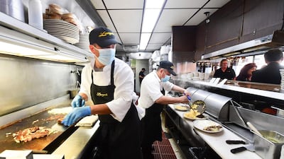 Kitchen staff who are continuing to wear face masks prepare breakfast at Langer's Delicatessen-Restaurant in Los Angeles, California. AFP