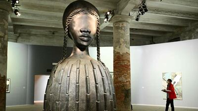 A visitor views "Brick House", a 2019 bronze sculpture by artist Simone Leigh, during a press day at the 59th Venice Art Biennale in Venice on April 19, 2022. (Photo by Vincenzo PINTO / AFP) / RESTRICTED TO EDITORIAL USE - MANDATORY MENTION OF THE ARTIST UPON PUBLICATION - TO ILLUSTRATE THE EVENT AS SPECIFIED IN THE CAPTION